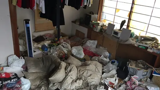 室内に物が散乱したゴミ屋敷の清掃イメージ